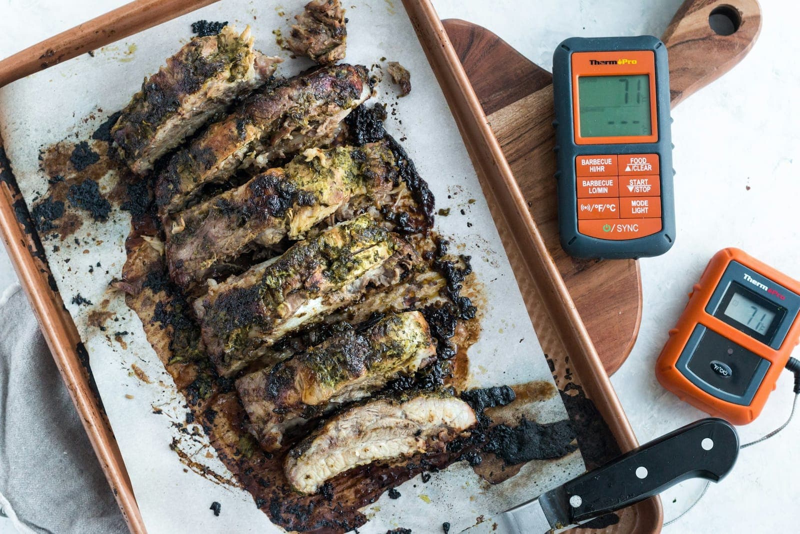 Digital probe thermometer resting beside a rack of smoked ribs