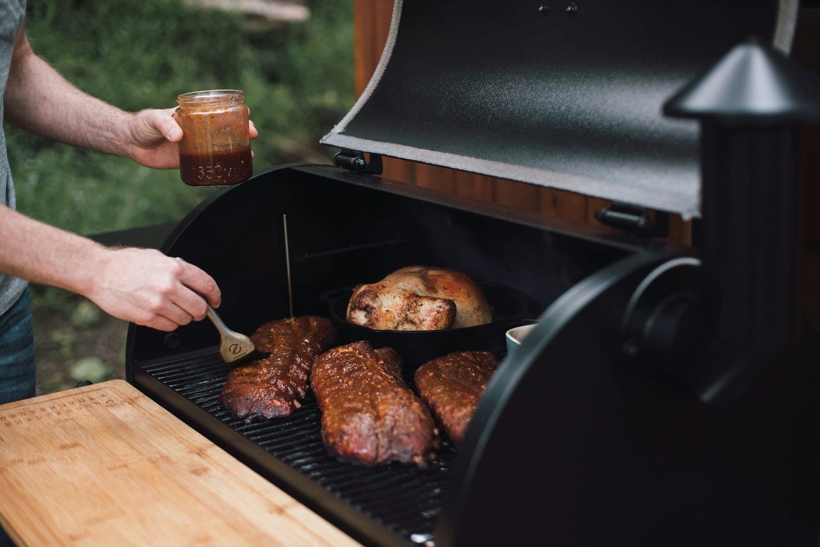 Basting meat on the grates of a pellet smoker